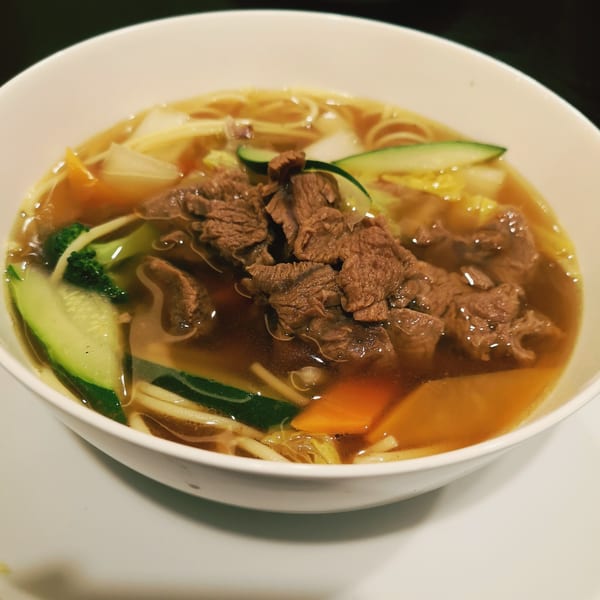 A bowl of ijji Noodle House's beef noodle soup with vegetables and broth.